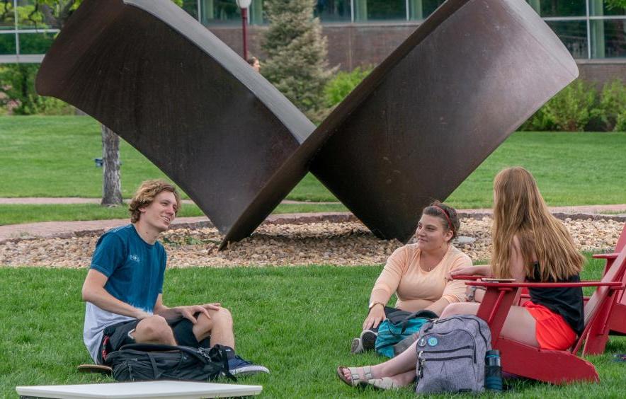 three people chatting outside on a lawn